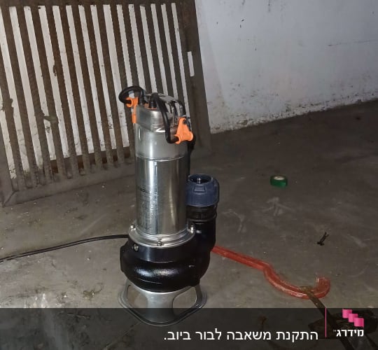 משאבה תעשייתית על רצפת בטון ליד סורג מתכת